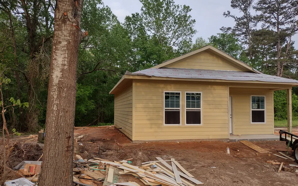 Newly sided home with windows and a front door installed